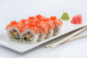 sushi or rolls on a long plate, wooden sticks, red ginger and wasabi