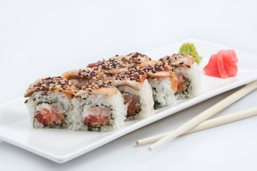 sushi or rolls on a long plate, wooden sticks, red ginger and wasabi