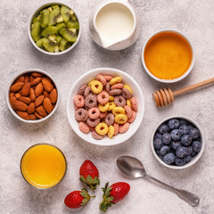 Breakfast with colorful cereal rings, fruit, milk, juice.