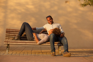 Obraz premium happy couple sitting on park bench outside