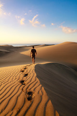 Men walking among Maspalomas sand dunes. Gran Canaria island.