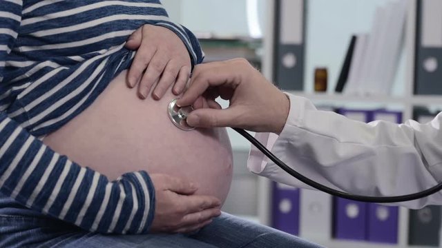 Doctor examining pregnant woman with stethoscope. Health care control during pregnancy.