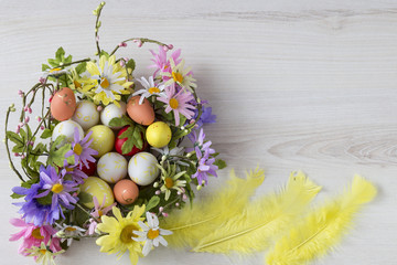 Fototapeta na wymiar on a light wooden background a floral wreath, eggs and feathers