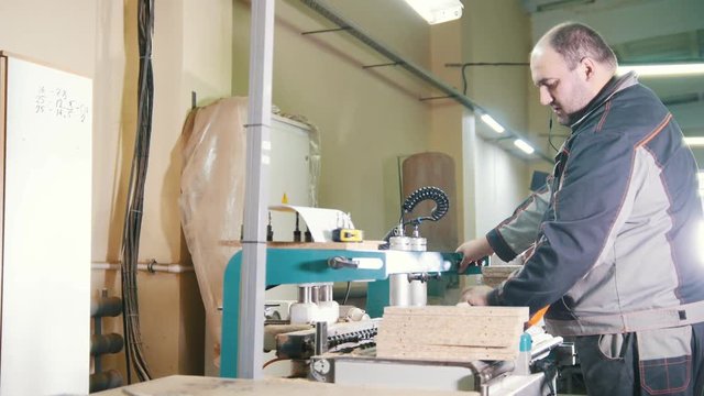 Carpenter cut a wooden workpiece on a furniture factory