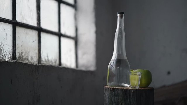 Apple brandy, rustic retro atmosphere. Bottle and single shot glass with alcohol drink and two green apple fruit.