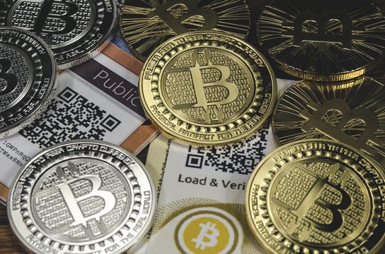 Bitcoin coins laying on paper wallet with QR code for contactless payment