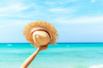 Fototapeta na wymiar Summer Travel. Happy and Relax woman hand holding big hat on white sand beach, freedom lifestyle.