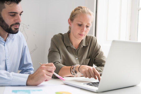 Young businesswoman and man typing on laptop at office desk meeting