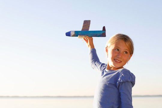 Young girl, outdoors, playing with toy aeroplane