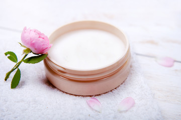 Fototapeta na wymiar pot of moisturizing face cream and beautiful flower on a white wooden background. natural organic cosmetic facial.