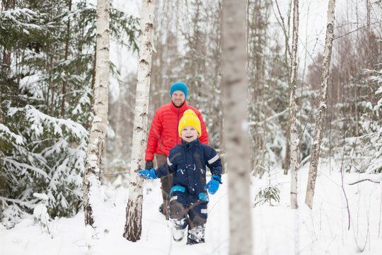 Man and son walking in snow covered forest
