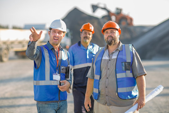 Three quarry workers in discussion, at quarry site