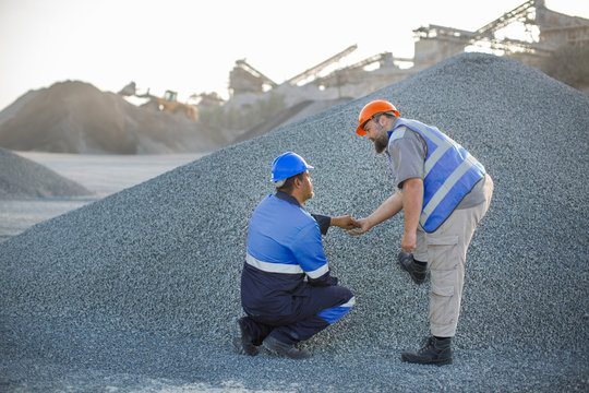 Two quarry workers in quarry, checking aggregate