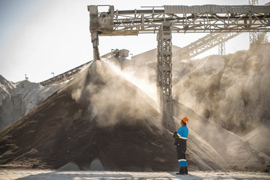 Quarry worker standing beside pile of aggregate in quarry