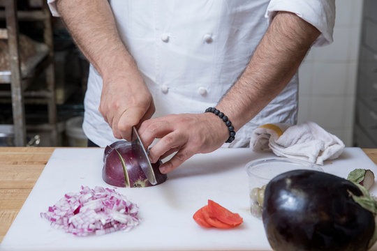 Cropped view of chef slicing red onion - Powered by Adobe
