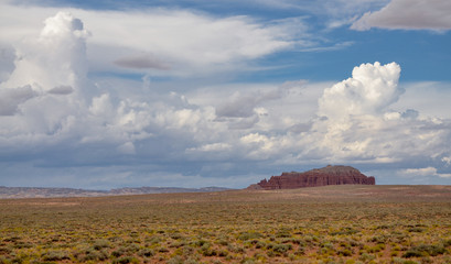 white clouds over red sandstone Gilson butte in the deserted plains of south central Utah