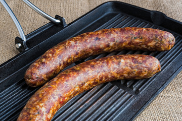 Two raw sausages on a grill, ready for cooking