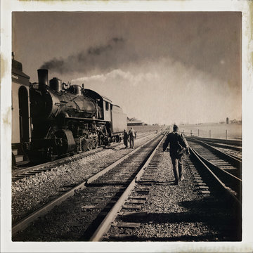 Men walking near old steam locomotive against sky