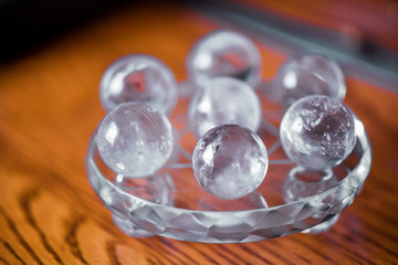 Macro shot of transparent crystal balls with colorful ornaments and sun reflections in it, on turquoise glass pad standing on a pine dining table.Fortune telling. Love, money, luck, success