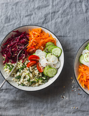 Bulgur, spinach, beets, carrots, cucumbers, tomatoes, daikon - balanced healthy food lunch. On a grey background, top view. Comfort autumn winter vegetarian food