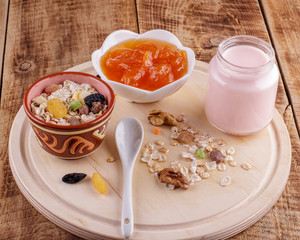Healthy breakfast. Ceramic bowl with oat flakes, dried fruits, nuts on wood background