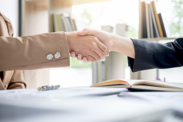 Obraz na płótnie Canvas Two business woman shaking hands during a meeting to sign agreement and become a business partner, enterprises, companies, confident, success dealing, contract between their firms