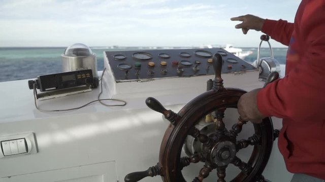 Hands at the helm of the yacht