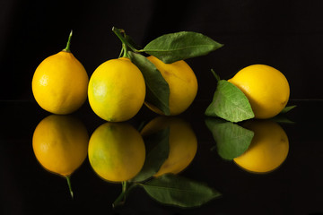 Lemons on a dark background with reflection.