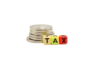 Close up image of the alphabet dices which are arranged for a word TAX in front of stack of coins, and isolated on white background and the clipping path embedded.