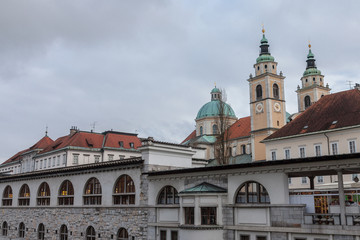 Fototapeta na wymiar Central Market of Ljubljana, capital city of Slovenia, taken during a cloudy rainy day, with the Ljubljanica river on foreground and the Ljubljana Cathedral (Saint Nicholas Church) in the background.