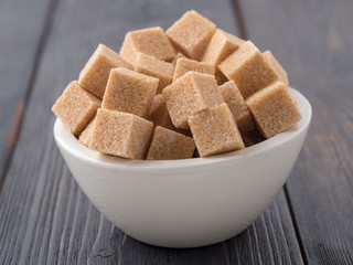 brown cane sugar in a white Cup on a brown wooden background, side view