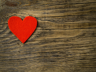 single bright red heart on dark vintage texture old wood background, symbol of Valentine's day, copy space for text, top view.