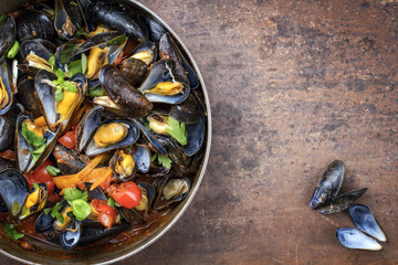 Traditional barbecue Italian blue mussel in red wine sauce as top view in a casserole with copy space right