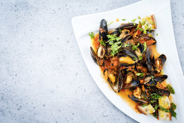 Traditional Italian blue mussel in white wine sauce as close up on a plate with copy space left