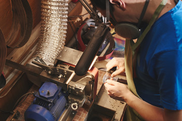 Making of a knife. Master sharpens a blade on the machine closeup in the Studio