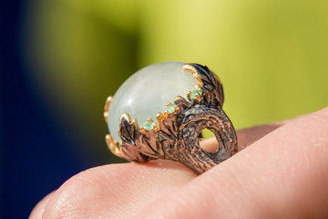 Macro shot of silver engagement ring on colorful, sparkling background. Prehnite stone with emerald. Prehnite is birthstone for zodiac sign of Libra, stone of unconditional love. Healing crystals.