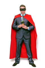 Super hero man holds in hands a little green tree in the pot isolated on white background. Save nature.