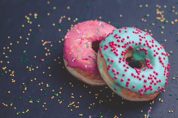 Donuts with colorful icing on a dark background.