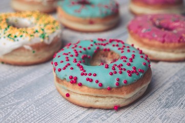 Donuts with colorful icing on a wooden background.