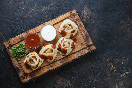 Steamed meat dumplings manti with tomato sauce, sour cream and greens on a wooden tray. Top view on a dark brown stone background with space