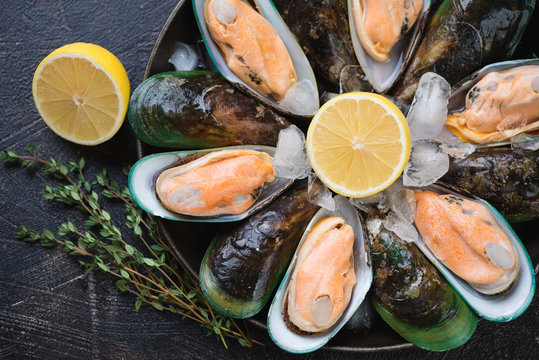 Close-up of fresh iced green mussels with lemon and thyme, horizontal shot, above view