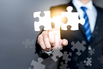 Mergers and acquisition concept with consultant touching icons of puzzle pieces representing the...