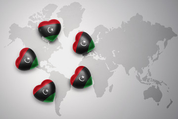 five hearts with national flag of libya on a world map background.