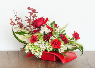 Fototapeta na wymiar Fancy floral arrangement of red and white flowers, with the addition of decorative grass in red container