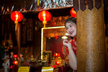 Obraz na płótnie Canvas Portrait of beautiful asian woman wear cheongsam on light of lantern background,Happy chinese new year,Thailand people