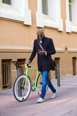 Fototapeta na wymiar Handsome young man using mobile phone and fixed gear bicycle in the street.