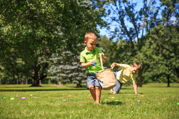 Fototapeta premium children collect Easter eggs in the park. cheerful boys pick up colorful eggs. The concept of Easter Egg Hunt