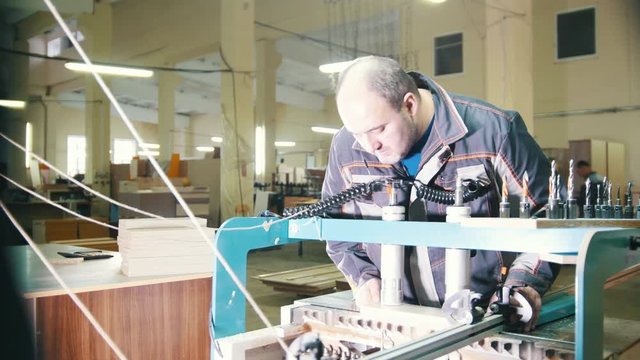 Worker carpenter handles a wooden fragment on a furniture factory