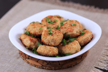 Fried cutlets on a white plate on a table on a gray background.
