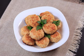 Fried cutlets on a white plate on a table on a gray background.